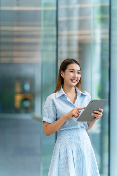 istock Young Asian Woman Using A Tablet, Looking Away Contented 2165387834