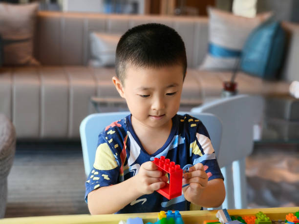 istock The little boy built a tower out of wooden blocks. Cute kids stack toys while developing fine motor skills and hand-eye coordination. The boy is playing with blocks or wooden blocks 2165388826