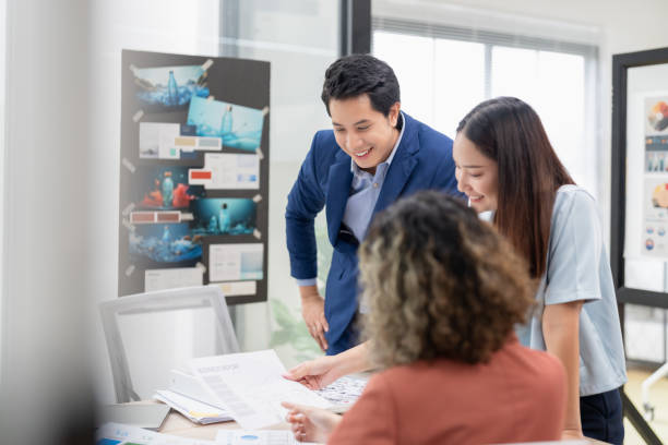 istock Asian business team brainstorming ideas in modern office. Creative professionals sharing innovative strategies during a collaborative meeting. Contemporary workspace with teamwork diverse perspective 2165389704
