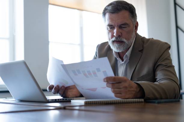 istock Mature businessman working with document in modern office, reading contract, analyzes graph 2165389854