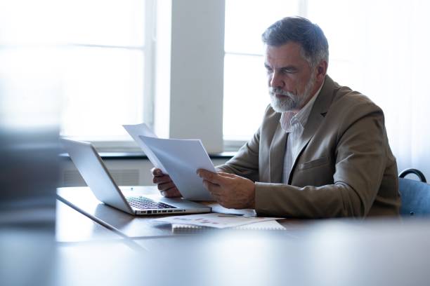 istock Mature businessman working with document in modern office, reading contract, analyzes graph 2165389856