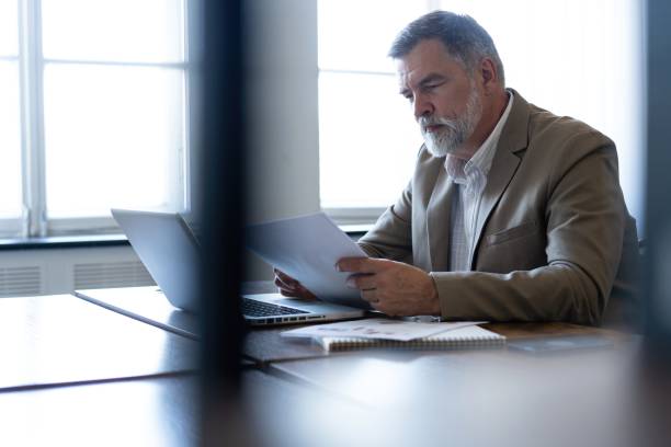 istock Mature businessman working with document in modern office, reading contract, analyzes graph 2165389862