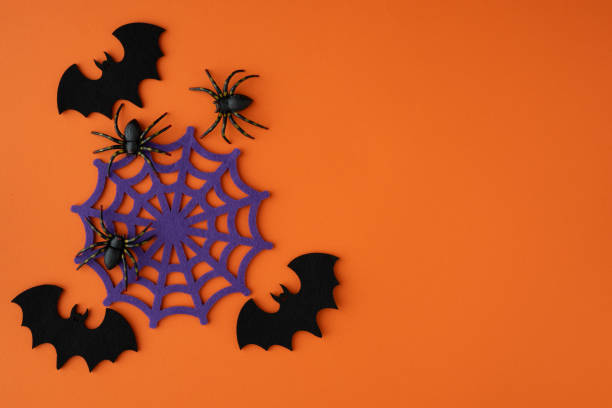 istock Purple spider web with spiders and bats, Halloween decoration on orange background. 2165391714