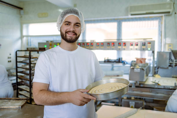 istock Man holding large pan of dough in the bakery 2165392040