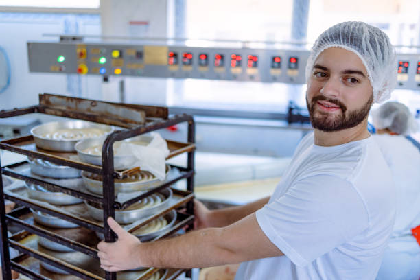 istock Man pushing rack of baking pans in bakery 2165392045
