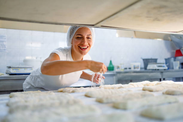 Joyful baker preparing dough for baking in industry.