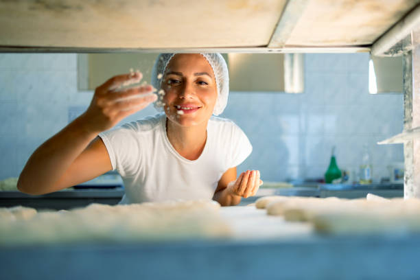 istock Baker enjoying dough preparation with flour sprinkle. 2165392160