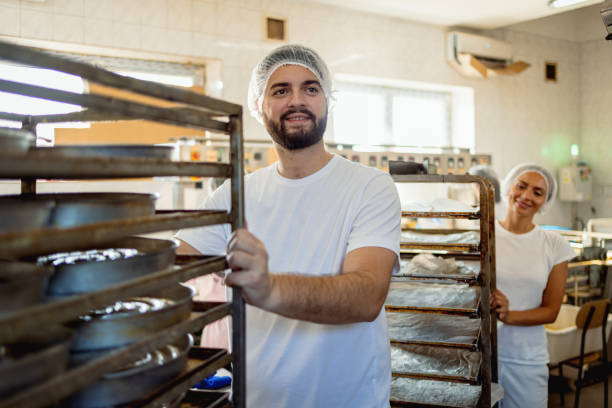 istock Two workers moving trays in bakery, man and woman. 2165392282