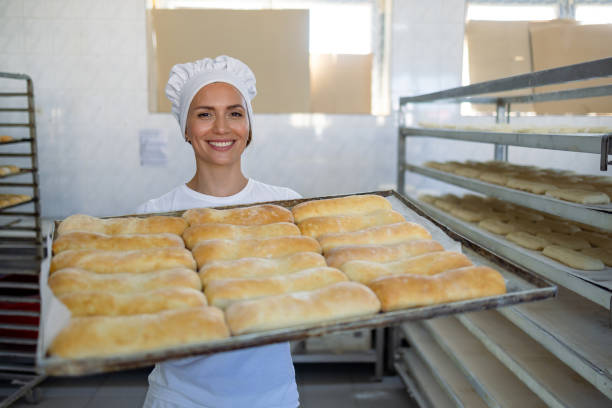 istock Happy baker presenting fresh loaves of bread. 2165392773