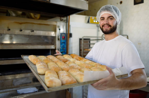 istock Smiling male baker presenting fresh baked bread. 2165392811