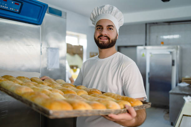 istock Male baker presenting freshly baked golden bread. 2165393555