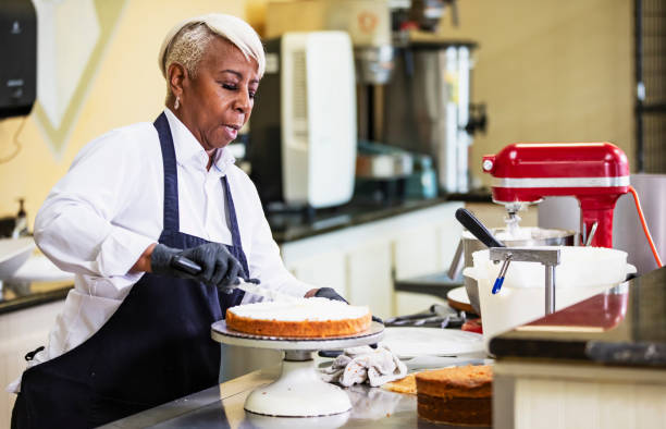 istock Senior black woman making cake in bakery, frosting layer 2165396690