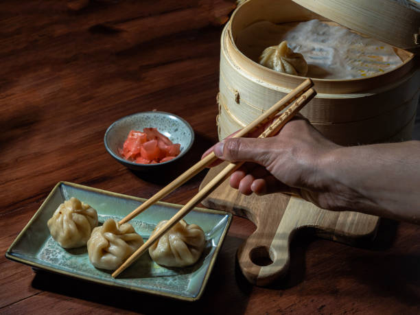 istock One hand grasps with chopsticks a steamed buns prepared in a bamboo steamer 2165398480