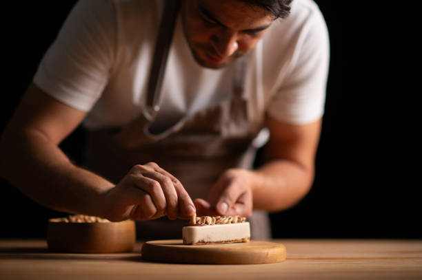 A male pastry chef making a cake with peanuts