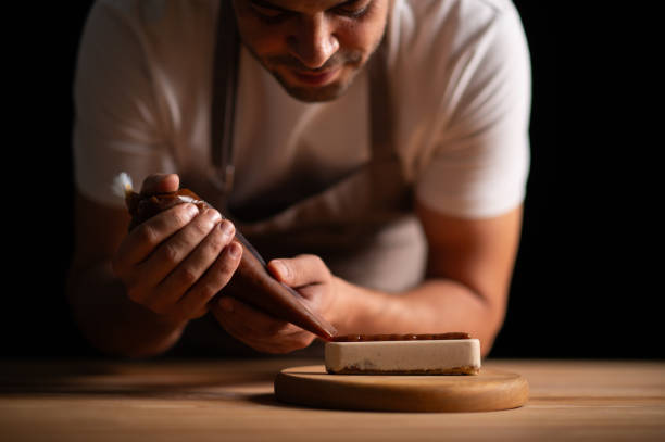 istock A male pastry chef squeezing chocolate sauce from icing bag to a cake 2165398720