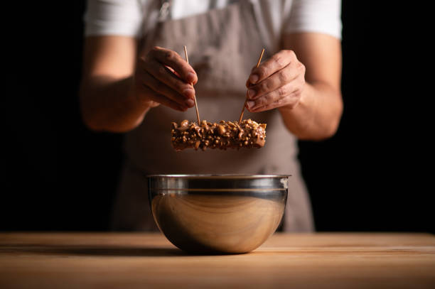 istock A male pastry chef dipping up peanut cake into chocolate sauce 2165398836