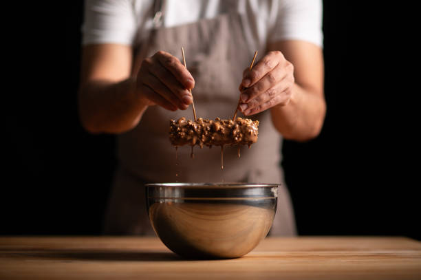 istock A male pastry chef dipping up peanut cake into chocolate sauce 2165398870