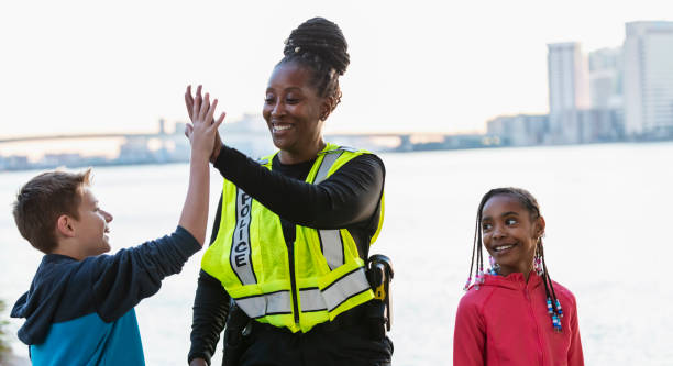 istock Policewoman walking with children in community, high five 2165398939