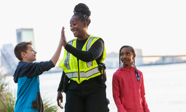 istock Policewoman walking with children in community, high five 2165398945