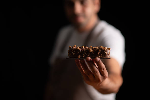 A male pastry chef holding a peanut cake