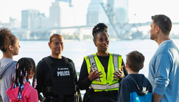 istock Policewomen talking on city waterfront with two families 2165399074