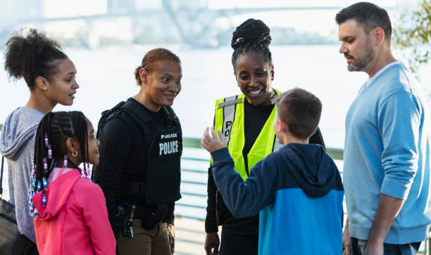 istock Policewomen talking on city waterfront with two families 2165399104