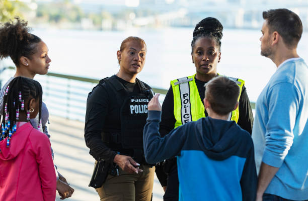istock Policewomen talking on city waterfront with two families 2165399111