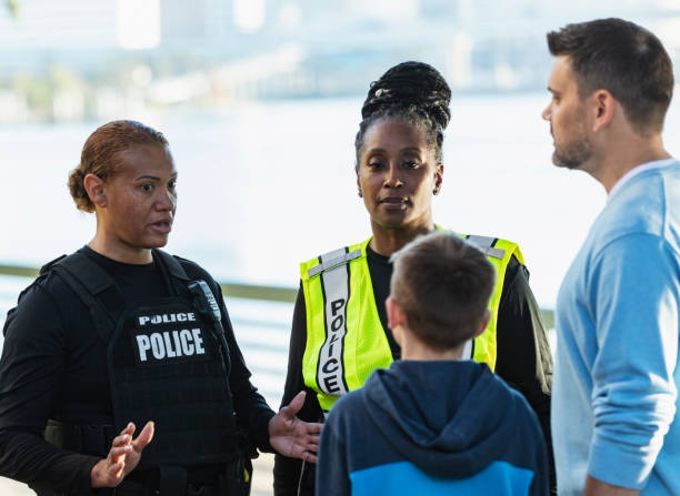 istock Policewomen talking on city waterfront with father, son 2165399113