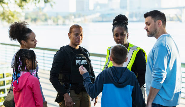 istock Policewomen talking on city waterfront with two families 2165399115
