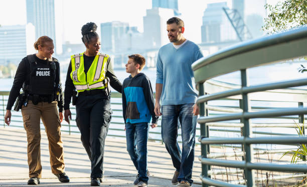 istock Policewomen talking on city waterfront with father, son 2165399117