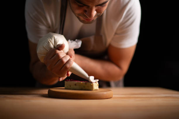 istock A male pastry chef squeezing cream from icing bag to a cake 2165399233