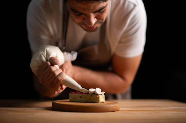 istock A male pastry chef squeezing cream from icing bag to a cake 2165399239