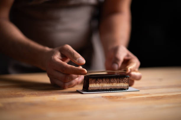 A male pastry chef decorating a chocolate cake