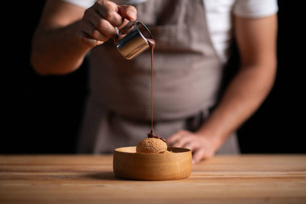 istock A male pastry chef pouring chocolate sauce on profiteroles 2165399689