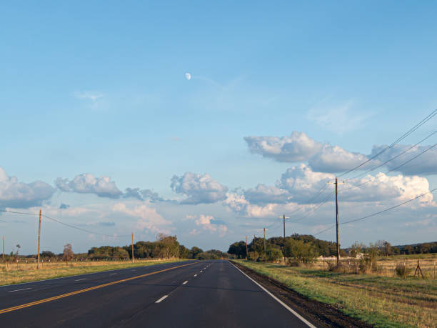 A soft landscape photograph with the moon visible in the daytime.