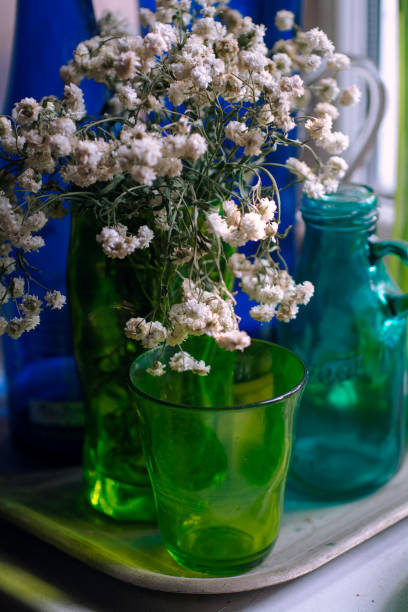 stilllife with white flowers and green and blue glass vase