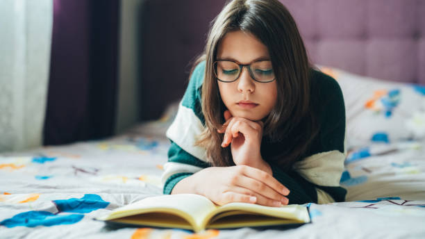 istock Girl reading a book at home 2165405290