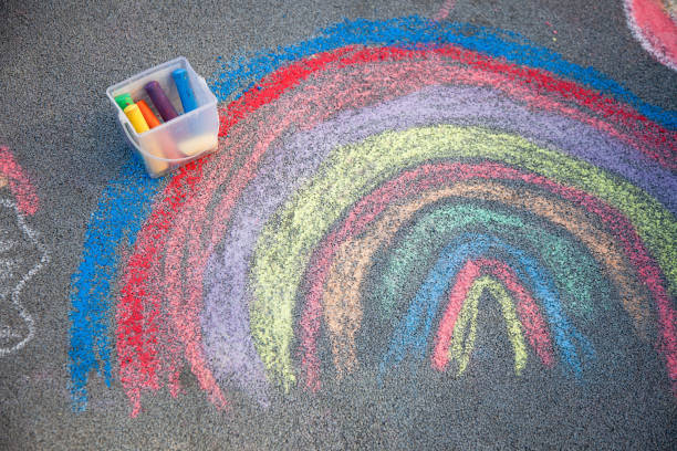 istock Sidewalk chalk drawing. A rainbow painted on the asphalt. Kids activities 2165405482