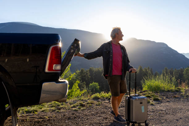 istock Mature man leaves vehicle with suitcase 2165406296