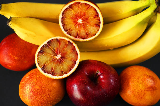 istock Several ripe yellow bananas next to a red apple, oranges 2165407015