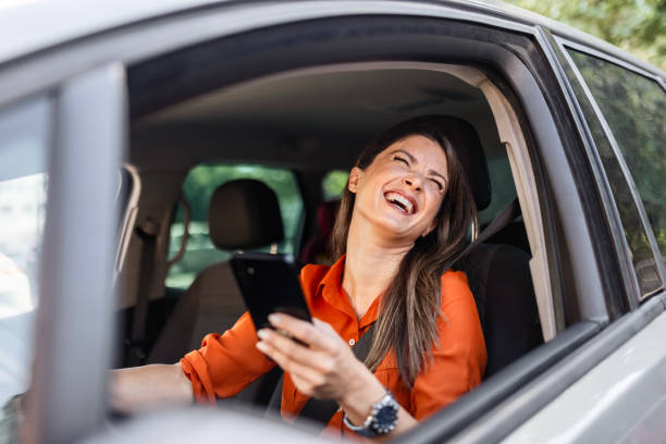 istock Woman Behind the Wheel Using Her Phone Smiling 2165407894