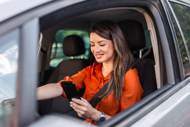 istock Young Woman Behind the Wheel Using Her phone 2165407895