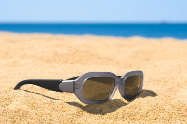 istock Sunglasses close up at a sandy beach 2165408324