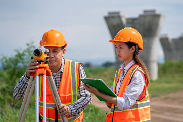 istock Survey team is working with a theodolite and road construction plans. Civil engineers are taking measurements with surveying tools during the construction. 2165409379