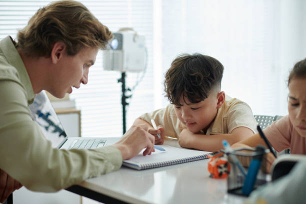 istock Guiding Child with Homework at Classroom Desk 2165410718