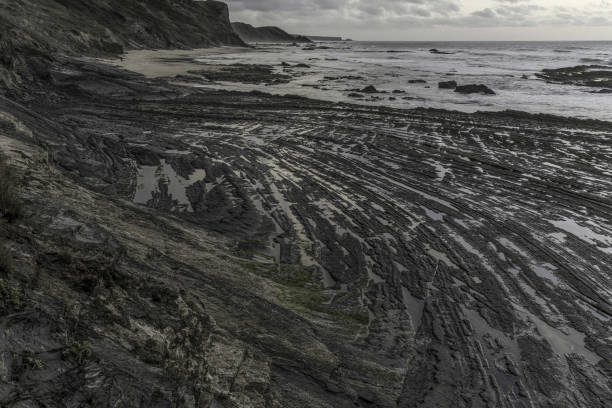 Moody sky with dramatic cloud formations over Carriagem Beach, Portugal. Rugged coastline and rock formations create a striking and atmospheric scene at dusk.