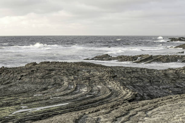 Moody sky with dramatic cloud formations over Carriagem Beach, Portugal. Rugged coastline and rock formations create a striking and atmospheric scene at dusk.