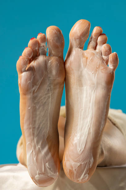 istock Female soles with foot mask on blue studio background. 2165413188
