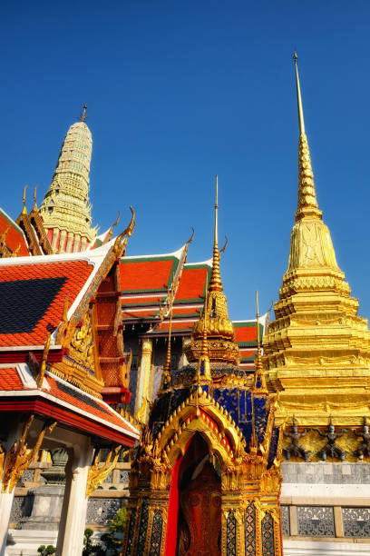 istock An enchanting low-angle shot frames a Thai temple's red rooftops, opulent golden highlights, and an imposing white spire against the canvas of a crystal-clear blue sky. 2165414040