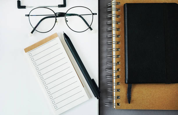 istock Notepad with to-do list next to notepads, pen, glasses 2165415183